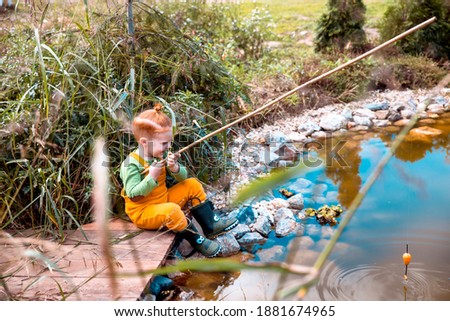 Little Boy fishing in small creek outdoors, playing in sunny day Child with a fishing rod by the water. Young fisherman relaxing and playing on a dock on a pond