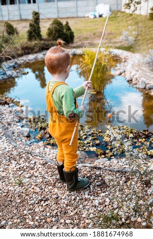 Little Boy fishing in small creek outdoors, playing in sunny day Child with a fishing rod by the water. Young fisherman relaxing and playing on a dock on a pond