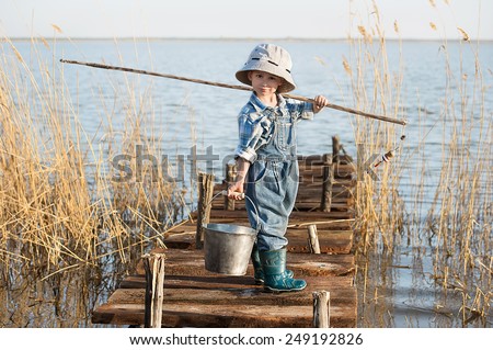 Little boy is fishing at sunset on the lake