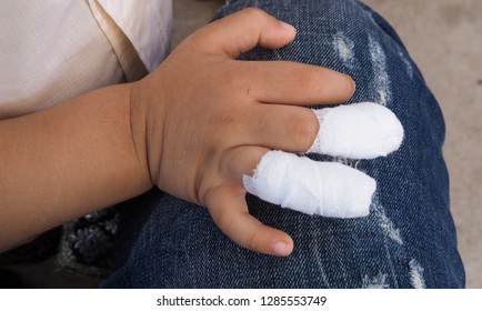 The Little Boy Gets An Accident. Wounds From Sharp Objects On Fingers. Doctor Used White Gauze Cloth Wrapped In The Hands And Placed On The Knees Wearing Jeans.