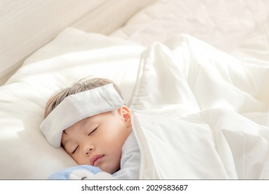 Little Boy Gets High Fever Lying On Bed With Cold Compress, Wet Washcloth On Forehead. Soft Focus. Copy Space.