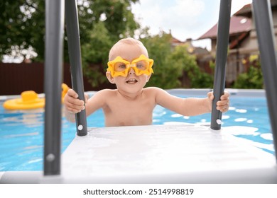 Little boy getting out of swimming pool by ladder outdoors - Powered by Shutterstock