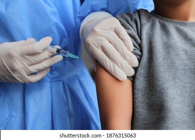 Little boy getting vaccinated from Covid-19. A young doctot's hand holding a  vaccine syringe. - Powered by Shutterstock