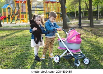 Little Boy And Little Girl Baby Walk With A Stroller For Dolls. 