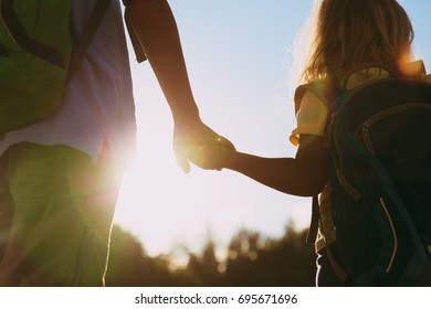 little boy and girl with backpacks holding hands at sunset