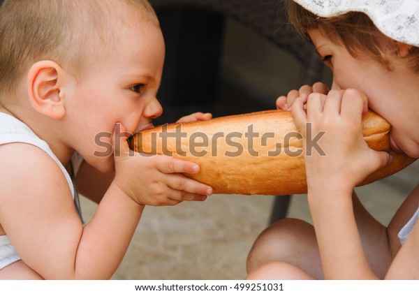 little boy and girl\
bite bread on both sides