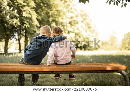 Little boy girl, brother sister bonding sitting on park bench. Family, sibling relationships 
