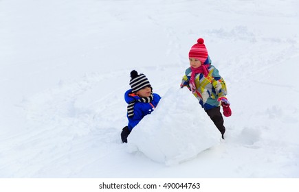 Little Boy And Girl Building Snowman In Winter