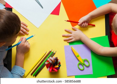 Little boy and girl doing crafts. Children ready to draw on colored paper. Top view.