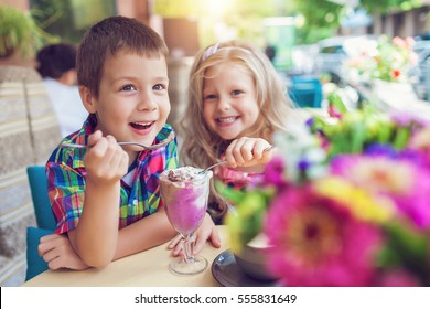Kleiner Junge mit Mädchen, die in einem Café im Freien Eis essen