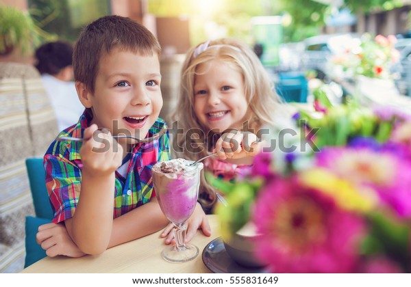 アウトドアカフェでアイスクリームを食べる女の子と小さな男の子 の写真素材 今すぐ編集