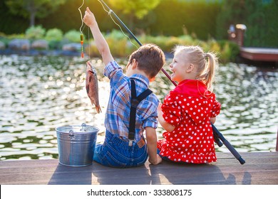 Kleiner Junge und Mädchen, die in einem Fluss fischen. Auf einem Holzsteg sitzen