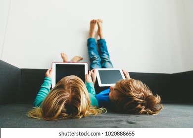 little boy and girl looking at touch pad at home - Powered by Shutterstock