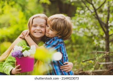 Little boy and girl in love in garden. Cheerful kids playing on park outdoors. Summer portrait of happy cute children. Lovely child, first kids love. Happy childhood. Kids friendship and kindness.
