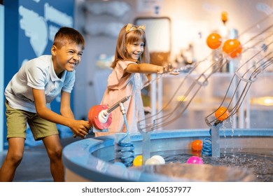 Little boy and girl play with balls, learning physical phenomena in an interesting way, having fun in a science museum with interactive models - Powered by Shutterstock