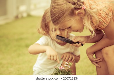 little boy and girl playing with a magnifying glass at day time - Powered by Shutterstock