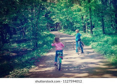 little boy and girl riding bike in nature