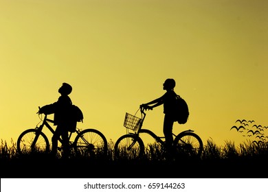 Little Boy And Girl Riding Bikes At Sunset, Active Kids Sport, Asian Kid,Silhouette A Kid At The Sunset, Happy Time.