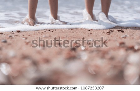 Little boy and girl standing in sea water on the beach in summer