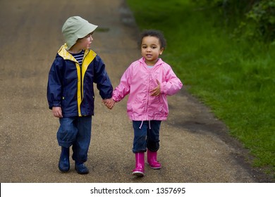 A Little Boy And Girl Wearing Wellington Boots Holding Hands And Walking Through A Country Park