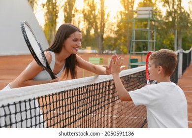 Little boy giving high five to his mother on tennis court - Powered by Shutterstock