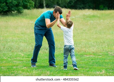 Little Boy Giving High Five To His Father In Park - Powered by Shutterstock