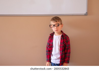 Little Boy With Glasses On The Sidelines Stands At The School Board. Back To School Concept