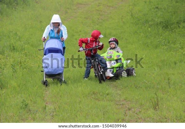 little boy goes for drive on electric quad bike.\
Tver Russia 2012. Sunny summer day. mother with a pram. electric\
ATV quad. little boy of 5 years risk riding ATV quad bike in race\
track. quadbike