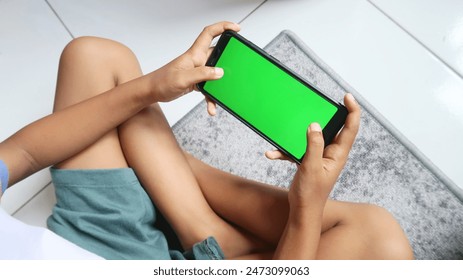 A little boy with a green screen handphone or gadget  - Powered by Shutterstock