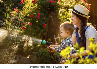 little boy and happy mother gardener watering garden with hose - Powered by Shutterstock