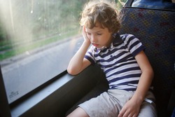 The Little Boy Has Fallen Asleep In The Bus. The Tired Child Sleeps, Having Leaned Against A Window.