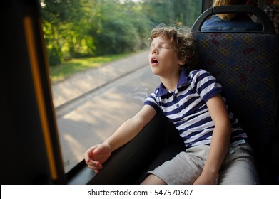 The Little Boy Has Fallen Asleep In The Bus. The Tired Child Sleeps, Having Leaned Against A Window.