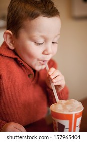 Little Boy Having Fun Blowing Bubbles Through A Straw Into His Chocolate Millksake