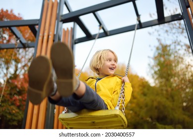 Little boy having fun on a swing on the playground in public park on autumn day. Happy child enjoy swinging. Active outdoors leisure for child in city - Shutterstock ID 2030400557
