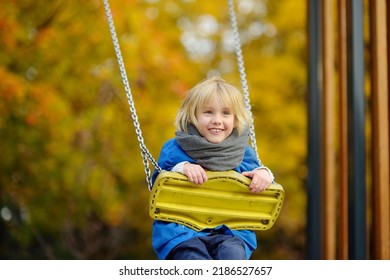 Little boy having fun on a swing on the playground in public park on autumn day. Happy child enjoy swinging. Active outdoors leisure for child in city - Shutterstock ID 2186527657