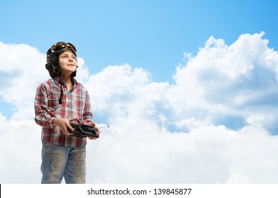 little boy in a helmet pilot keeps remote control, in the background sky and clouds