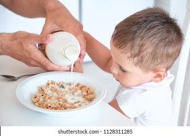 Little Boy Helps Dad Pour Milk Into Oatmeal. Quick Breakfast At Home