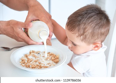 Little Boy Helps Dad Pour Milk Into Oatmeal. Quick Breakfast At Home