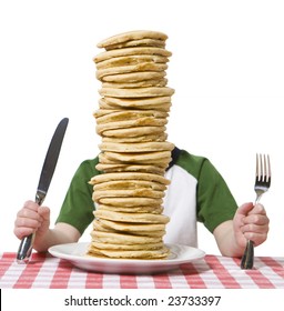 Little boy hidden behind  a giant plate of pancakes, with a knife and fork visible on a table cloth.