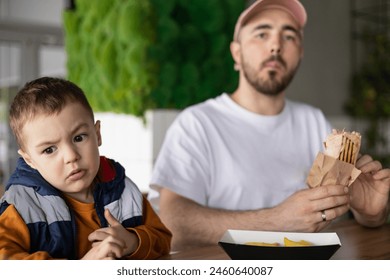 The little boy and his dad go together. Dad and son eating french fries. Dad and son time. - Powered by Shutterstock