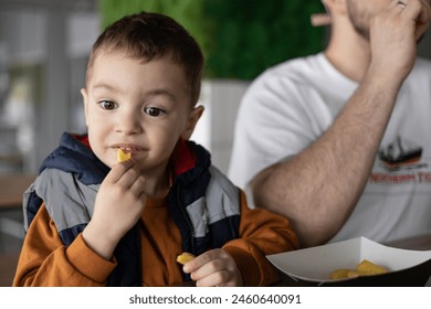 The little boy and his dad go together. Dad and son eating french fries. Dad and son time. - Powered by Shutterstock