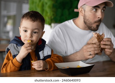 The little boy and his dad go together. Dad and son eating french fries. Dad and son time. - Powered by Shutterstock