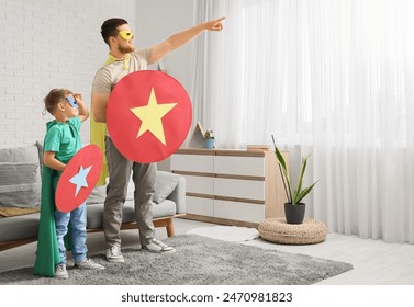 Little boy and his father in superhero costumes with paper shields at home - Powered by Shutterstock