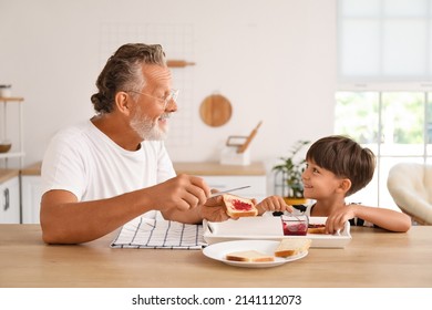 Little boy and his grandfather making sandwiches with jam at table in kitchen - Powered by Shutterstock