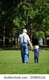 Little Boy With His Grandpa Walking In The Park