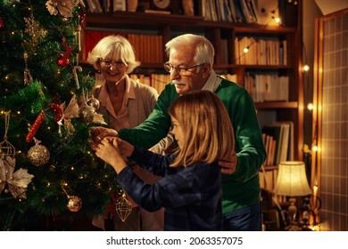 Little boy and his grandparents decorating Christmas tree in the living room. - Powered by Shutterstock