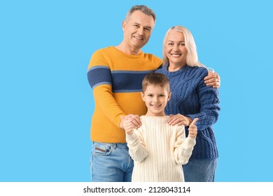 Little boy with his grandparents in warm sweaters on blue background