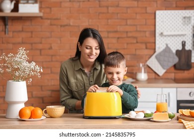 Little boy with his mother putting bread slices into toaster in kitchen