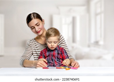 A little boy and his mother are talking and smiling while drawing together at the table at home. - Shutterstock ID 2238740691