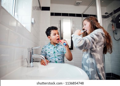 Little Boy And His Older Sister Are Brushing Their Teeth Together In The Bathroom At Home.